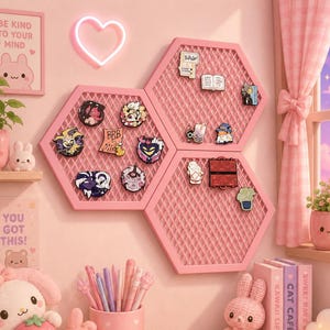 Op de afbeelding: Drie roze zeshoekige wandroosters tonen diverse emaille pins. De panelen hebben een gaasoppervlak met een ruitpatroon. De pins bevatten verschillende vormen en figuren, stevig bevestigd aan het rooster. De frames zijn effen roze en bieden een gestructureerd displayoppervlak voor het verzamelen en organiseren van kleine decoratieve items aan een muur.