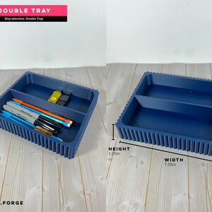 May include: A navy blue double tray with a ribbed exterior design. The tray features two rectangular compartments. Dimensions are labeled as 7.25 inches in width, 6.0 inches in length, and 1.25 inches in height. Pens and USB drives are inside.