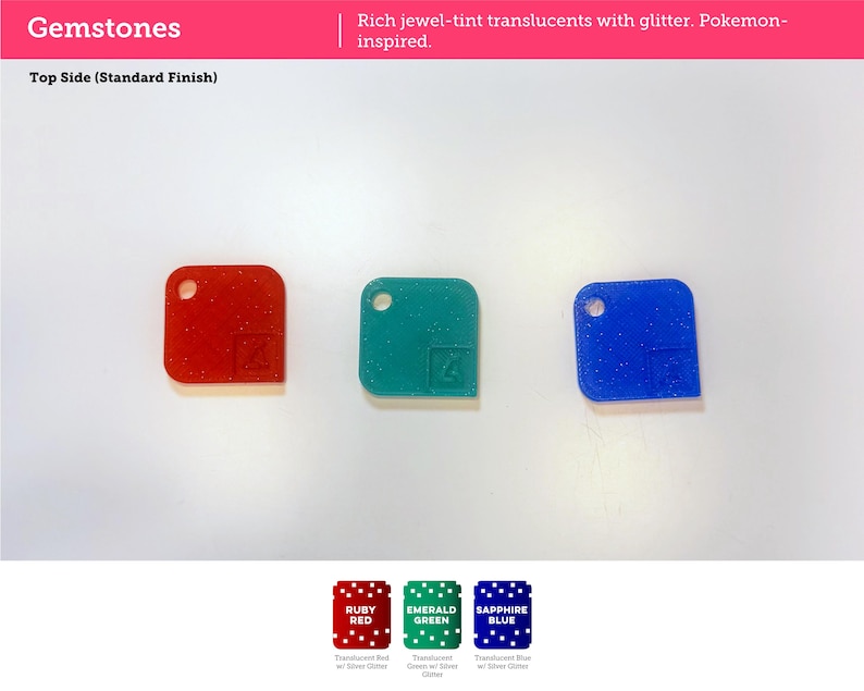 May include: Three square acrylic pieces in ruby red, emerald green, and sapphire blue with silver glitter. Each piece features a circular hole in the top left corner and a small embossed square icon in the bottom right corner. Text reads Gemstones.
