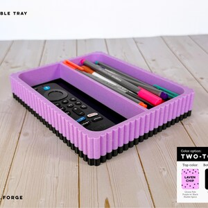 May include: A rectangular double tray with a lavender top and black base featuring a ribbed exterior. The tray contains a black remote control and several colorful pens. Text on the image reads DOUBLE TRAY and TWO-TONE.