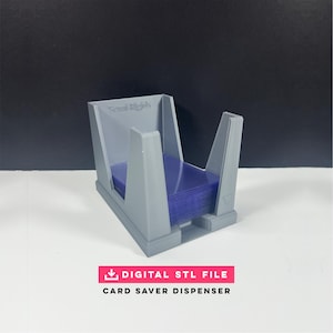 May include: A gray 3D-printed card saver dispenser holding a stack of blue cards. The dispenser has a rectangular base and angled sides. The text "DIGITAL STL FILE" and "CARD SAVER DISPENSER" are displayed on a pink rectangle.