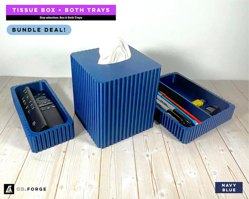 May include: A navy blue ribbed tissue box cover with a white tissue protruding from the top, accompanied by two matching navy blue ribbed rectangular trays. One tray holds a black remote control, and the other holds several pens and markers.