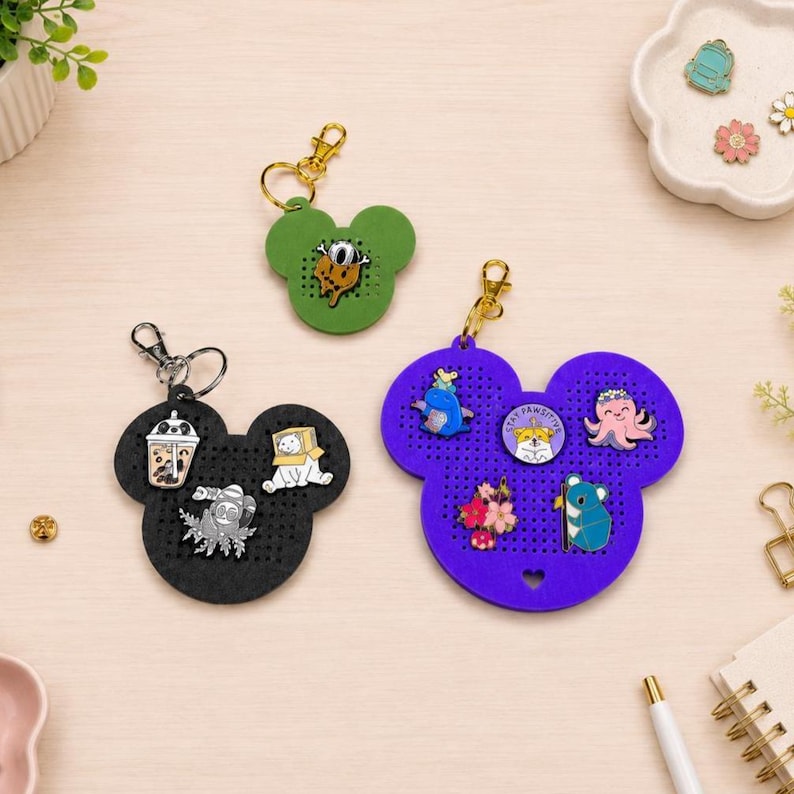 May include: Three mouse-shaped felt display boards with gold-tone keychains. The green board holds one pin, the black board holds three pins including a boba tea, and the purple board holds five pins featuring animals and flowers.