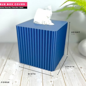 May include: A navy blue square tissue box cover with a vertical ribbed texture. The box measures 5.3 inches in height, 4.7 inches in width, and 4.7 inches in length. A white tissue is visible protruding from the top opening of the container.