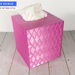 Pu&ograve; includere: Un copriscatola per fazzoletti quadrato di colore rosa vivace con un motivo a rombi in rilievo. La scatola presenta un'apertura superiore da cui fuoriescono fazzoletti bianchi. Il testo sull'immagine riporta WITH SHIELD e DIAMOND PATTERN STYLE.