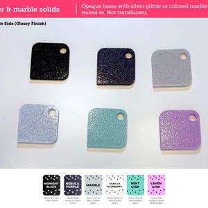 May include: Six square-shaped material swatches with rounded corners and a single circular hole. The colors include black, dark purple, gray, light blue, teal, and lavender, featuring either silver glitter or colored marble specks.
