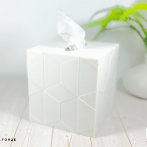Pu&ograve; includere: Un copriscatola per fazzoletti quadrato di colore bianco lucido con un motivo geometrico sfaccettato sulle superfici esterne. Un fazzoletto bianco sporge dall'apertura rettangolare sulla parte superiore. Il testo CD.FORGE &egrave; visibile nell'angolo.