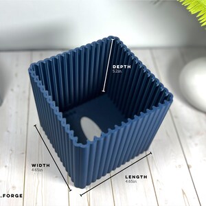 May include: A dark blue square planter with a ribbed exterior texture. The planter features printed dimensions of 4.65 inches in width, 4.65 inches in length, and 5.2 inches in depth. The base includes a drainage hole.