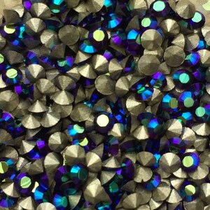 Könnte beinhalten: Nahaufnahme eines kleinen, durchsichtigen Behälters gefüllt mit schillernden blauen und grünen Strasssteinen.