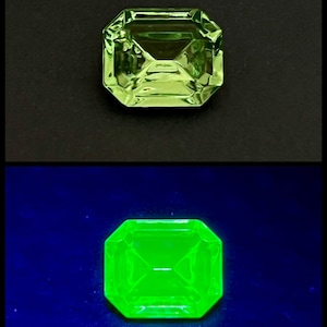 Può includere: Una pietra preziosa verde di forma quadrata, vista dall'alto. La pietra preziosa è illuminata da una luce UV, che la fa brillare di un verde brillante.