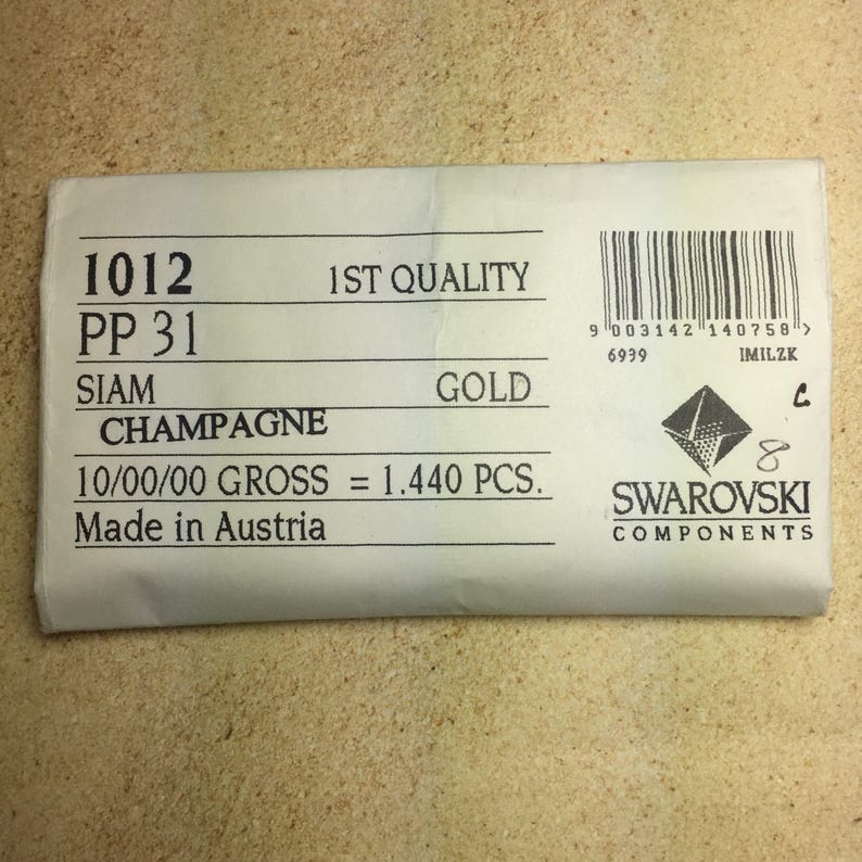 May include: A white paper bag with the text "1012 PP 31 SIAM CHAMPAGNE 1ST QUALITY GOLD 10/00/00 GROSS = 1.440 PCS. Made in Austria" and a black and white logo that says "SWAROVSKI COMPONENTS".