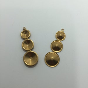 May include: Two sets of gold-colored, graduated disc-shaped earring components. Each set has three discs of increasing size, connected in a vertical line. Each component has a small loop at the top for attachment.