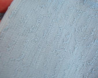 May include: Close-up of a light blue fabric with a textured, woven pattern.