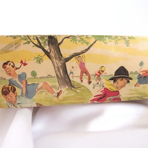 May include: A vintage box with a colorful illustration of children playing in a park. The box features a green tree, a blue sky, and a yellow sun. The children are wearing colorful clothing and are playing with toys, such as a kite and a bicycle.