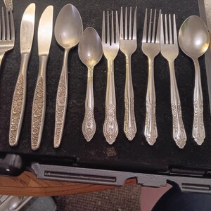 Puede incluir: Un juego de cubiertos con un diseño floral. El juego incluye tenedores, cucharas y cuchillos.