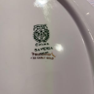 May include: White oval serving platter with a green and gold emblem that reads "SUPERIOR CHINA BAVARIA WARRANTED 22 CARAT GOLD". The platter has a smooth, glossy surface.