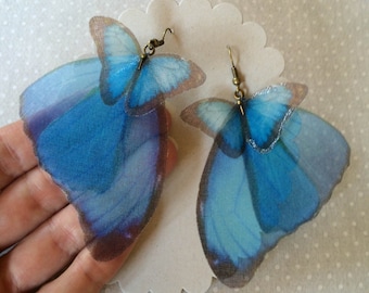 Peut inclure: Une paire de boucles d'oreilles en forme de papillon bleu avec des accents bruns. Les boucles d'oreilles sont en tissu et ont un aspect délicat et féminin.