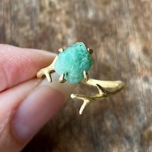 Peut inclure: Une bague en or avec un motif de branche et une pierre précieuse émeraude verte.