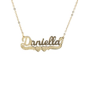 May include: Gold necklace featuring the name "Daniella" in a cursive script with two small hearts flanking the name.
