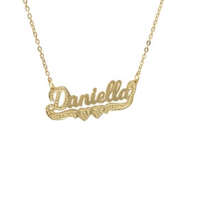 May include: A gold necklace with the name "Daniella" spelled out in cursive script with two small hearts on either side of the name.