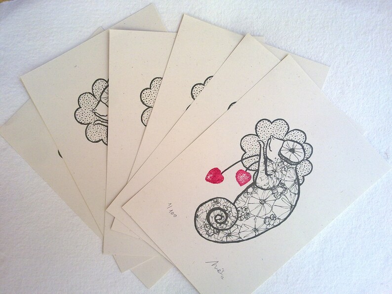 Puede incluir: Un conjunto de 7 tarjetas en blanco con una ilustraci&oacute;n en blanco y negro de un camale&oacute;n con corazones rojos en una cuerda. La tarjeta est&aacute; numerada 41/100 y firmada "Arie" en tinta negra.