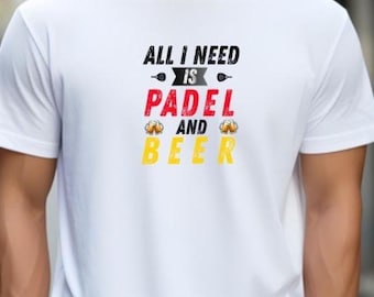 Może przedstawiać: Biała koszulka z napisem "ALL I NEED IS PADEL AND BEER" w kolorze czarnym, czerwonym i żółtym. Koszulka ma okrągły dekolt i krótkie rękawy. Projekt zawiera rakietę i kufle piwa.