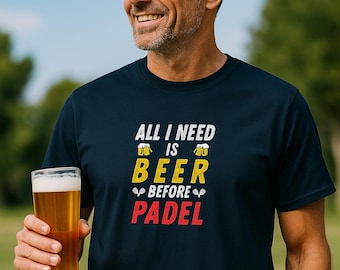 Może przedstawiać: Granatowa koszulka z napisem "ALL I NEED IS BEER BEFORE PADEL" w kolorze białym, żółtym i czerwonym. Zdjęcie przedstawia mężczyznę trzymającego szklankę piwa, z rozmytym zielonym tłem.