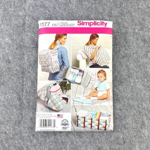 May include: A Simplicity 1177 sewing pattern envelope featuring illustrations of various baby accessories including a patterned backpack, a nursing cover, a car seat canopy, a baby bib, and a storage caddy. The package displays the text 1177 OS.