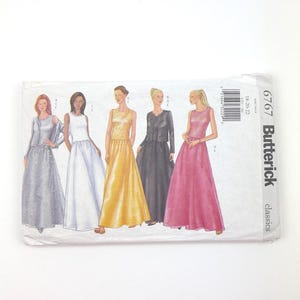 May include: A Butterick classics sewing pattern envelope featuring illustrations of five different formal gowns. The gowns are in various colors, including silver, white, gold, black, and pink. The envelope has a barcode and the number 6767.