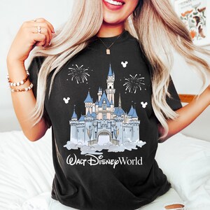 May include: Black t-shirt with a detailed illustration of Cinderella's castle, blue turrets, fireworks, and the text "Walt Disney World." The design includes white Mickey Mouse silhouettes.