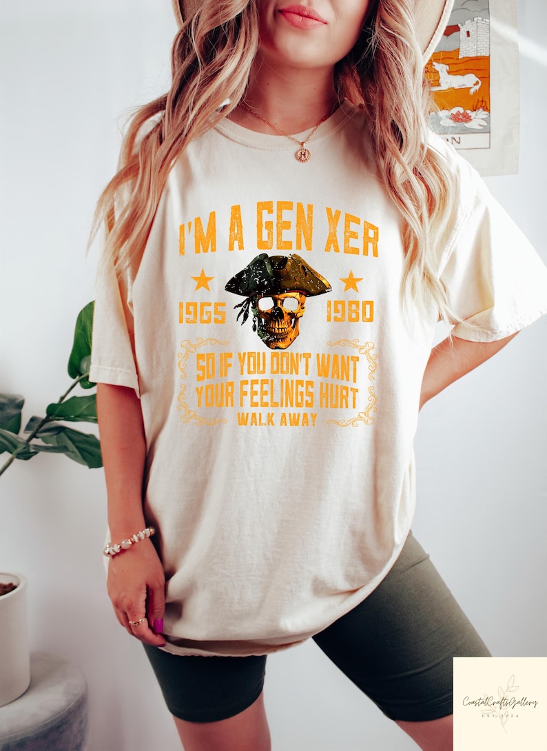 Puede incluir: Camiseta color crema con el texto "I'M A GEN XER" en naranja. El dise&ntilde;o incluye una calavera con sombrero de pirata, los a&ntilde;os 1965 y 1980, y la frase "SO IF YOU DON'T WANT YOUR FEELINGS HURT WALK AWAY."