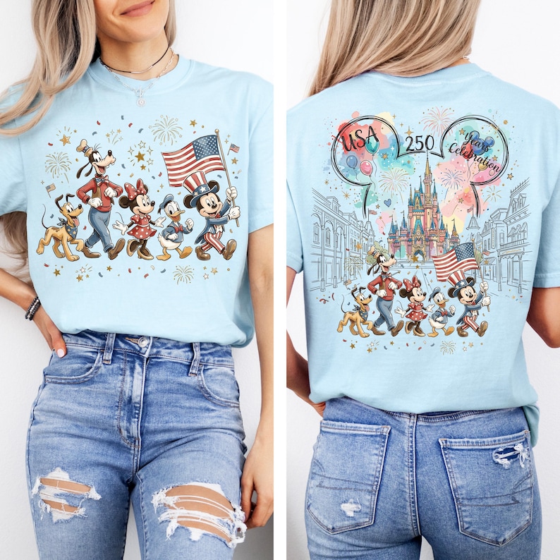 Peut inclure: Un t-shirt bleu clair avec un motif de personnages de dessin anim&eacute; marchant avec un drapeau am&eacute;ricain sur le devant. Le dos pr&eacute;sente un ch&acirc;teau, des feux d'artifice, des ballons et le texte USA 250 Years Celebration avec des illustrations.