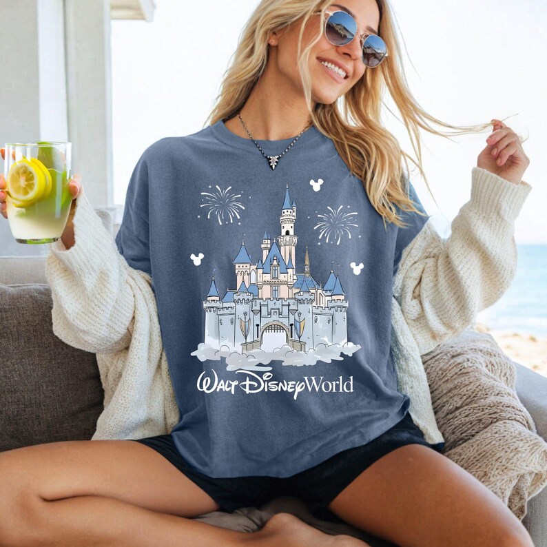 May include: A blue t-shirt with a castle design, fireworks, and Mickey Mouse silhouettes. The text "Walt Disney World" is printed below the castle. The shirt is a relaxed fit, suitable for casual wear and made of soft material.