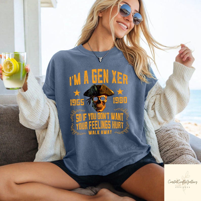 Puede incluir: Camiseta azul con el texto "I'M A GEN XER" y una calavera con un sombrero de pirata. La camiseta tambi&eacute;n incluye los a&ntilde;os 1965 y 1980, y la frase "SO IF YOU DON'T WANT YOUR FEELINGS HURT WALK AWAY."