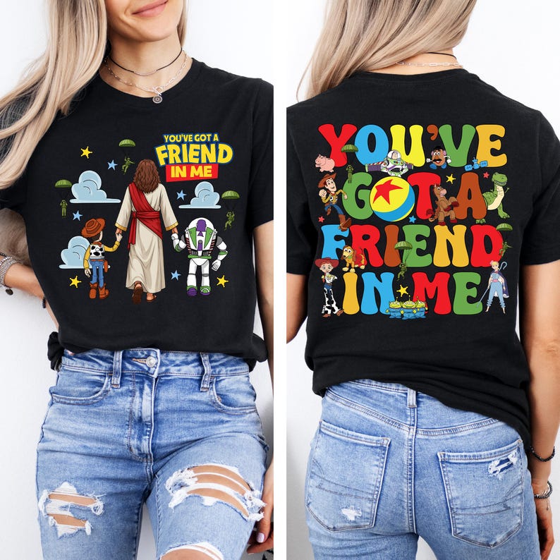 Op de afbeelding: Zwart T-shirt met de tekst "YOU'VE GOT A FRIEND IN ME" en tekenfilmfiguren. De voorkant van het shirt toont Jezus, Woody en Buzz Lightyear. De achterkant van het shirt heeft dezelfde tekst met meer karakters.