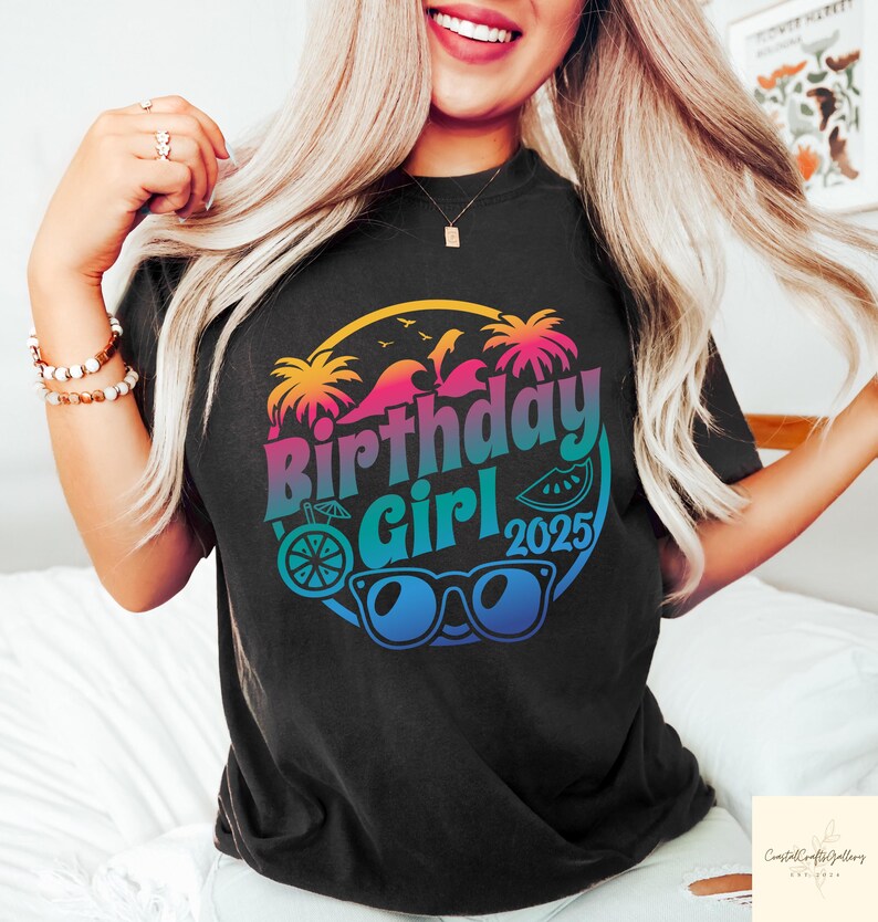 May include: Black t-shirt with a colorful graphic that says "Birthday Girl 2025". The design includes palm trees, waves, sunglasses, and a slice of watermelon. The text is in a gradient of pink, blue, and yellow.
