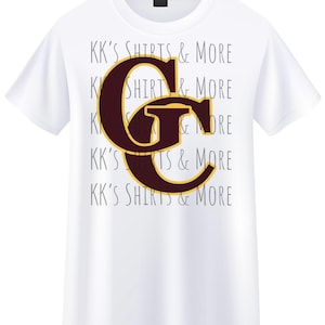 May include: White t-shirt with a large maroon and gold letter "G" graphic. The shirt also features the text "KK'S SHIRTS & MORE" in a repeating pattern in a light gray color. The shirt is made of a soft, comfortable material.