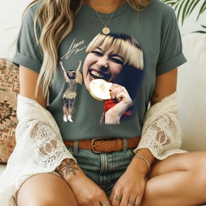 May include: A white ceramic mug with a black handle and the text "But First, Coffee" in a bold, black font. The mug is set against a blurred background, suggesting a cozy setting.