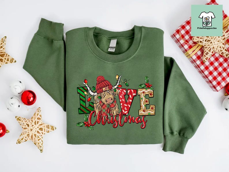 K&ouml;nnte beinhalten: Gr&uuml;ner Weihnachtspullover mit einem niedlichen Cartoon-Highland-Rind, das einen roten Weihnachtsmann-Hut tr&auml;gt und die Worte "Love Christmas".