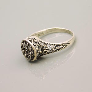 Pu&ograve; includere: Un anello in argento sterling con una testa circolare caratterizzata da un intricato motivo in filigrana traforata. La fascia &egrave; affusolata e presenta dettagliati motivi a volute sui lati. L'interno dell'anello reca il marchio 925.