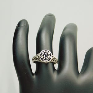Pu&ograve; includere: Un anello color argento caratterizzato da un elemento centrale ovale con un intricato design in filigrana traforata. La fascia presenta inoltre un motivo a volute dettagliato e testurizzato che si estende lungo i lati dell'anello, creando un aspetto coeso.