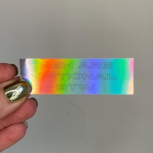 Men Are Optional BTW sticker with holographic effect, feminist humor, sarcastic statement, cheeky message against patriarchy