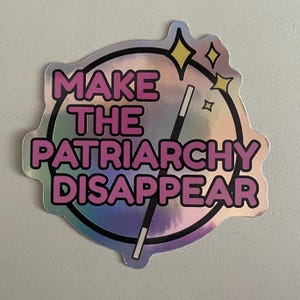 Könnte beinhalten: Holografischer Aufkleber mit dem Text "MAKE THE PATRIARCHY DISAPPEAR" in Pink, schwarz umrandet. Das Design beinhaltet einen Zauberstab und Sternakzente, gesetzt in einem schwarzen Kreis.