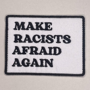 Könnte beinhalten: Rechteckiger, gestickter Aufnäher mit dem Text "MAKE RACISTS AFRAID AGAIN" in fetten, schwarzen Buchstaben auf weißem Grund. Der Aufnäher hat einen schwarzen Rand.