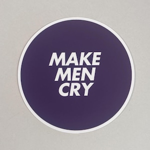 Könnte beinhalten: Ein runder Aufkleber mit weißem Rand. Die Mitte ist tiefviolett mit dem weißen Text "MAKE MEN CRY". Der Aufkleber befindet sich auf einem hellgrauen Hintergrund.