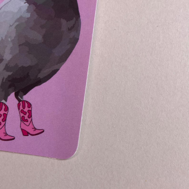 Pode incluir: Um cart&atilde;o retangular com uma ilustra&ccedil;&atilde;o gr&aacute;fica de um pombo cinzento a usar botas de cowboy cor-de-rosa brilhante com padr&otilde;es de manchas de vaca em cor-de-rosa escuro. A ilustra&ccedil;&atilde;o est&aacute; num fundo roxo claro s&oacute;lido com cantos arredondados.
