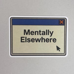Könnte beinhalten: Ein rechteckiger Aufkleber mit blauem oberen Balken und beigem Hintergrund. Der Text "Mentally Elsewhere" ist in schwarzer, fetter Schrift. Ein schwarzes Cursor-Symbol zeigt nach rechts unten. Der Aufkleber hat einen weißen Rand und ein rotes "X" oben rechts.