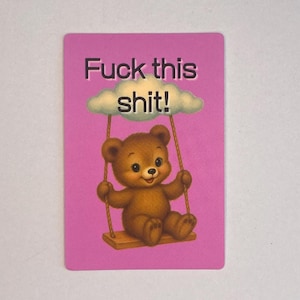 Peut inclure: Carte rose avec l'inscription "Fuck this shit!". Un ours en peluche brun souriant est sur une balançoire suspendue à un nuage.