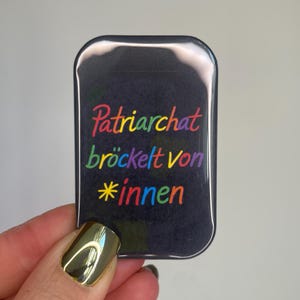 May include: A white ceramic mug with a black handle and the text "But First, Coffee" in a bold, black font. The mug is set against a neutral background, highlighting its simple design.