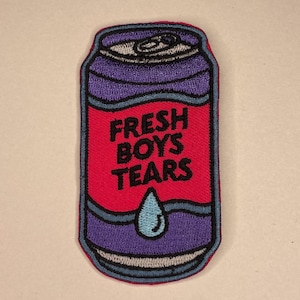 May include: Embroidered patch in the shape of a soda can. The can is purple with a red center and the words "FRESH BOYS TEARS" in white. A blue teardrop is at the bottom.
